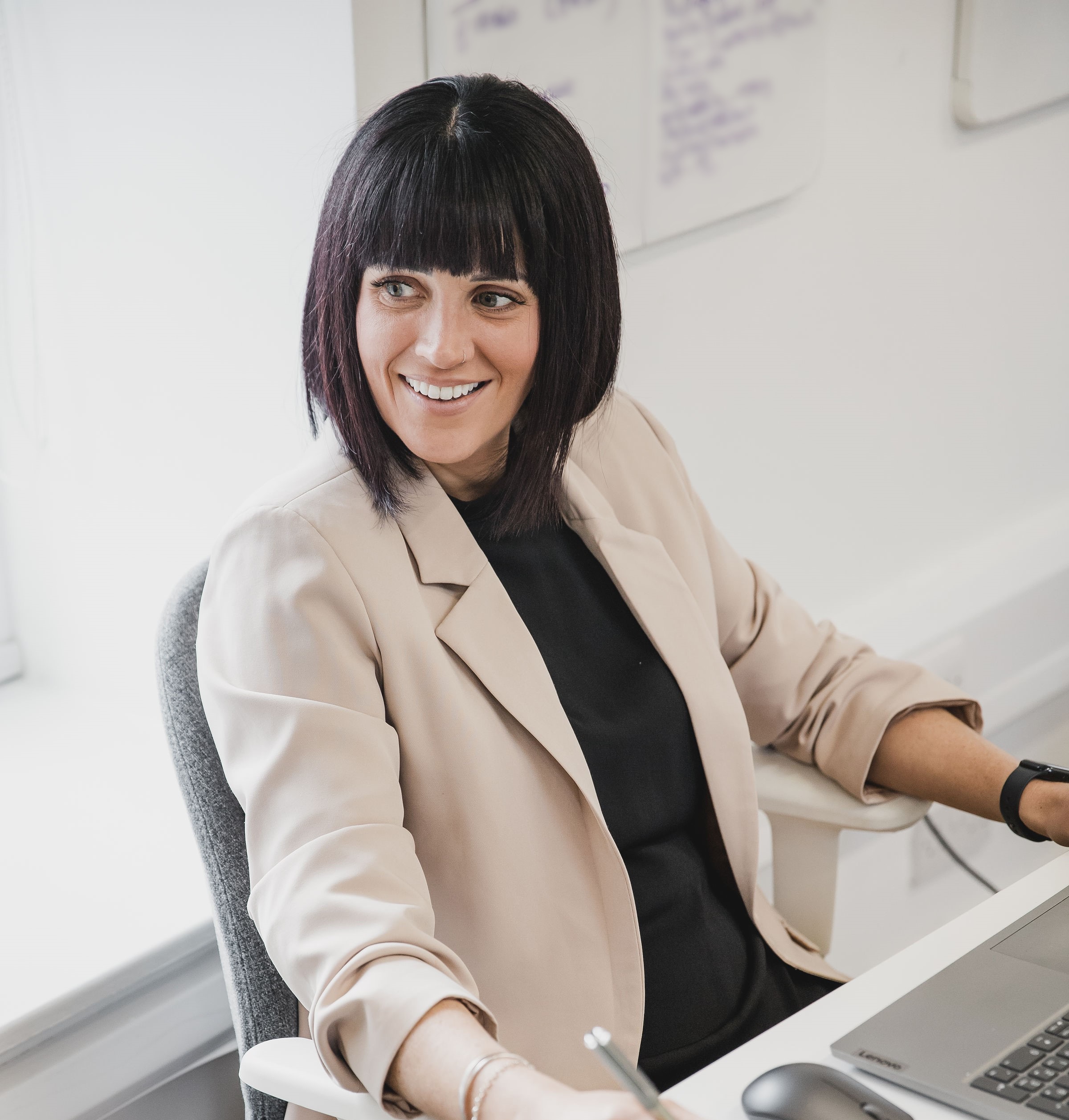 Photo of Gemma sat at her desk smiling at a colleague