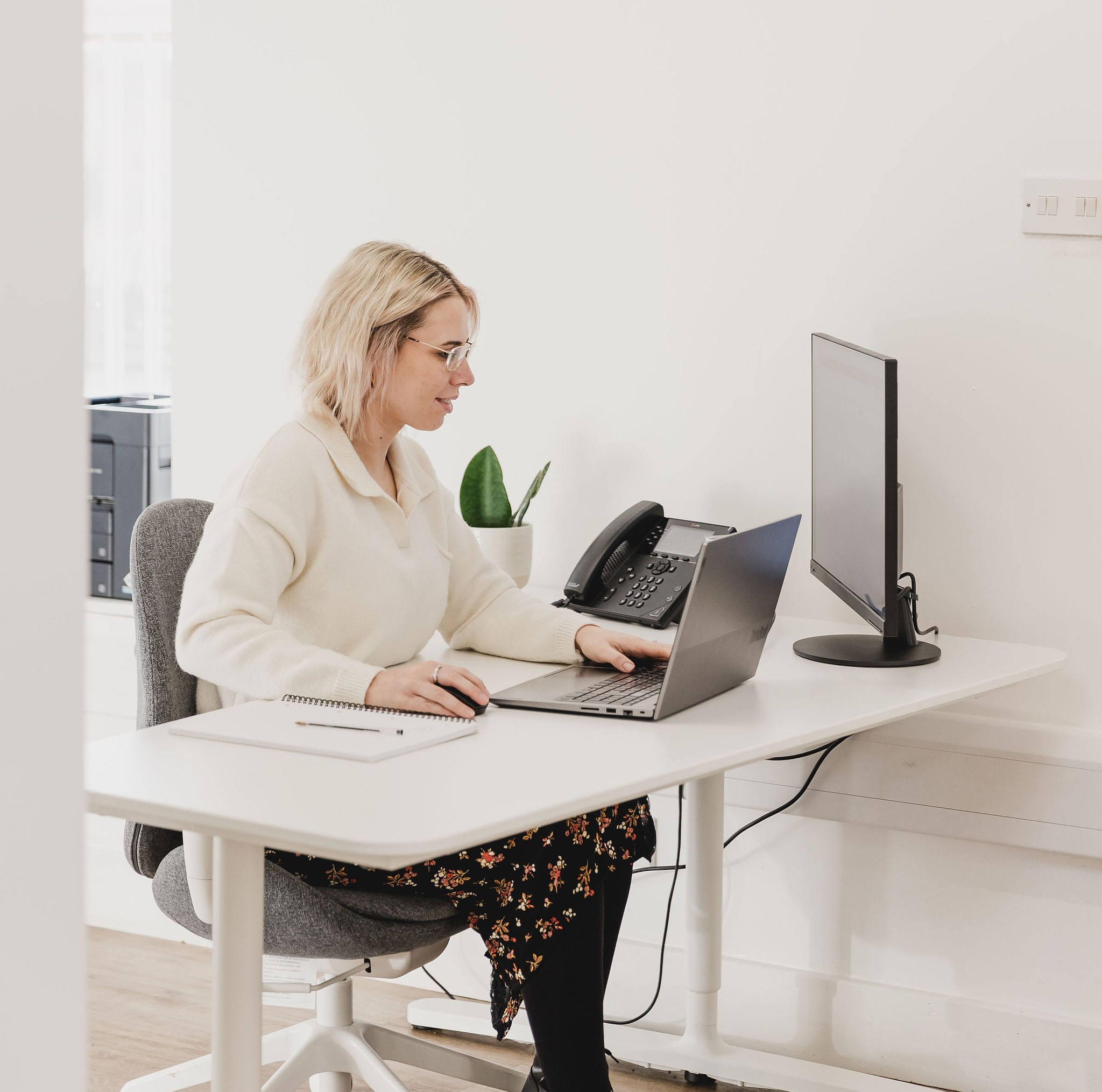 Photo of Megan working in a reception area on her laptop with a second screen